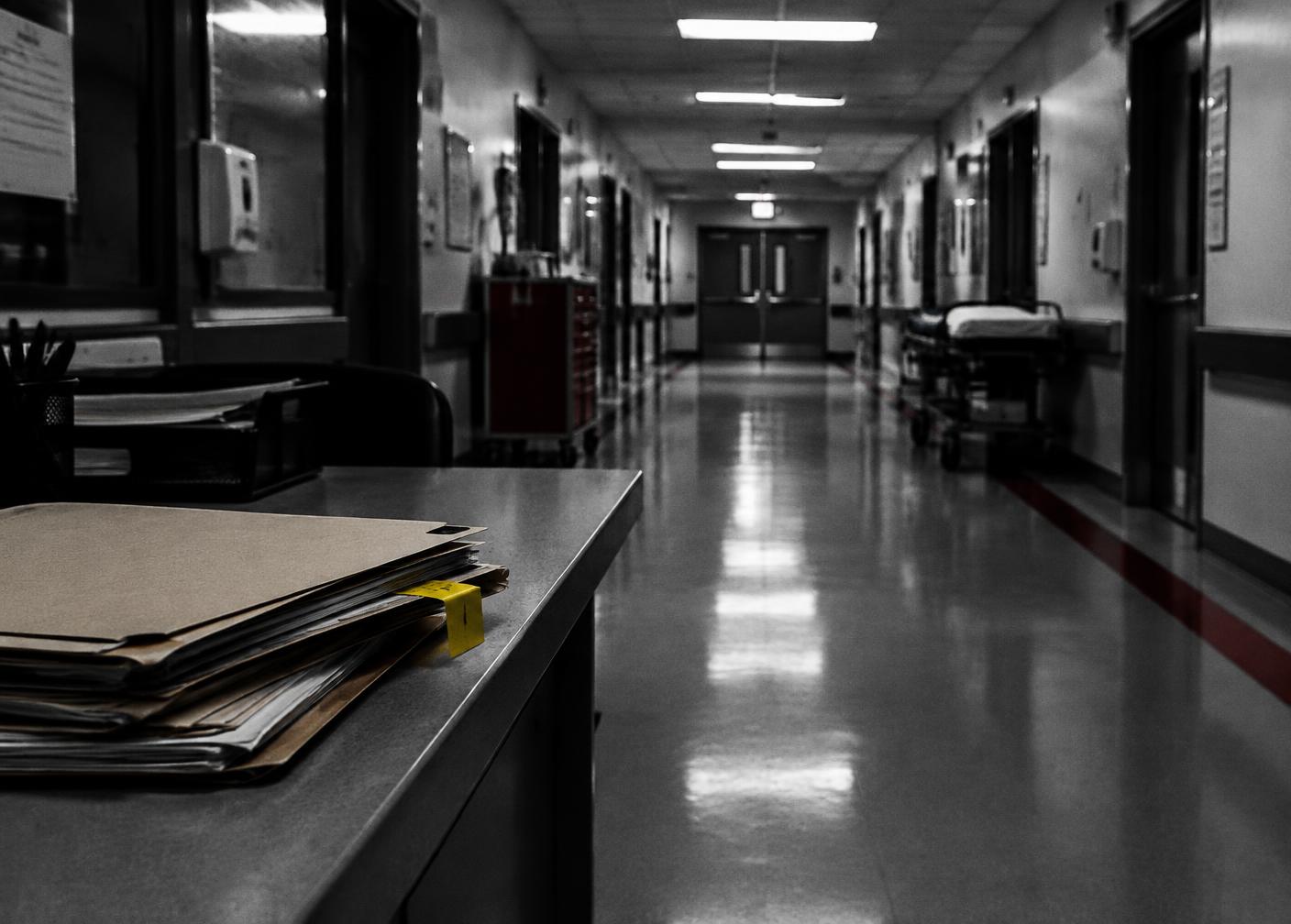 An empty hospital corridor beside a stack of medical files